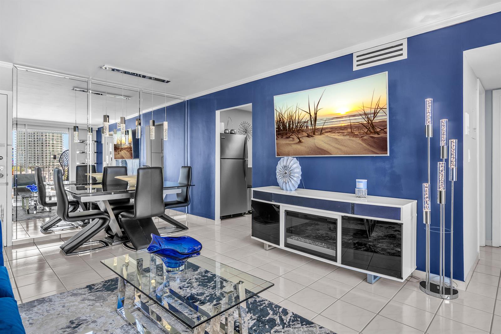 A dining and living area features blue walls, a glass coffee table, and a fireplace console — 6900 Bay Drive # 11i, Miami Beach FL 33141, MIAMI BEACH, FL