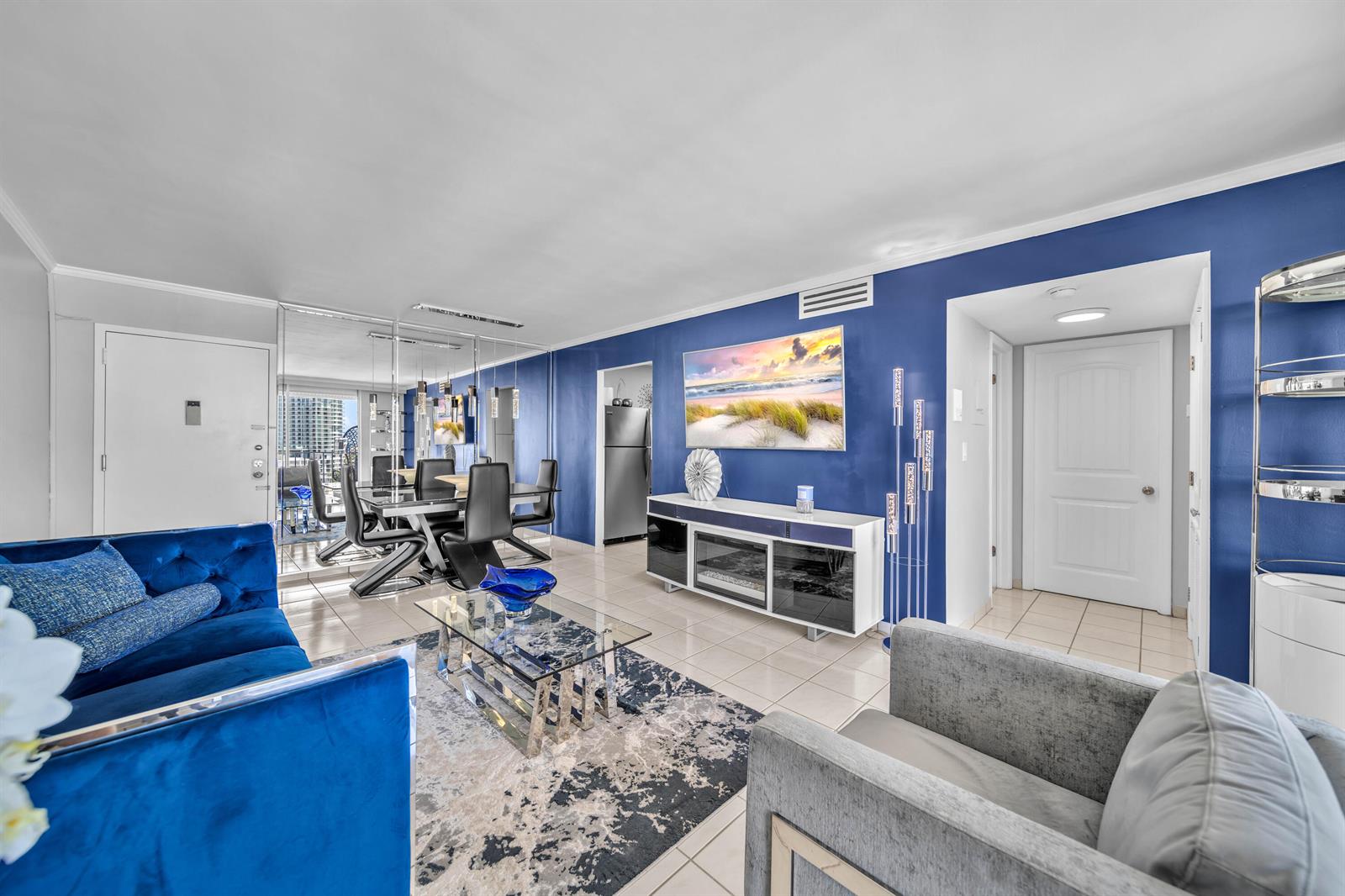 A living room features a blue accent wall, a velvet sofa, and a glass coffee table — 6900 Bay Drive # 11i, Miami Beach FL 33141, MIAMI BEACH, FL
