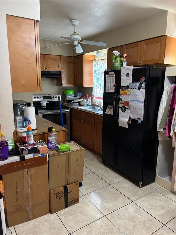 A kitchen features wood cabinets, a black refrigerator, a ceiling fan, and tiled flooring — 1602 BREN LEE COURT, ORLANDO, FL