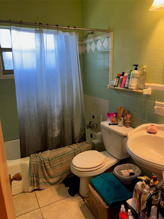 A bathroom features a shower curtain, a toilet, a pedestal sink, and green tiled walls — 1602 BREN LEE COURT, ORLANDO, FL