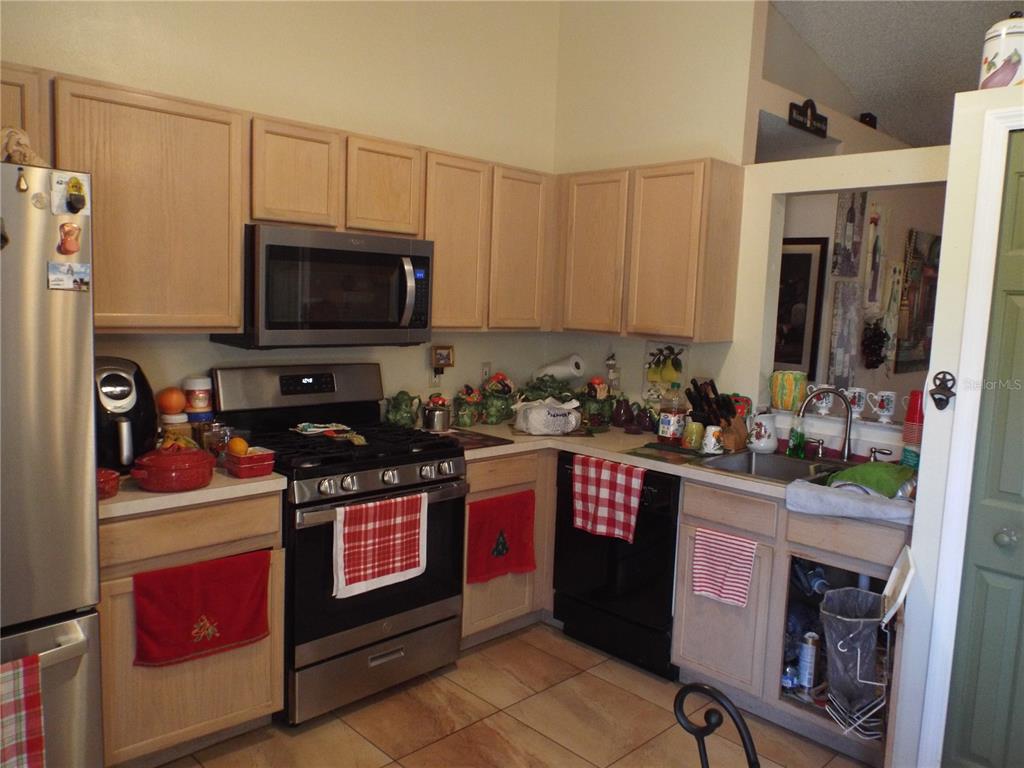 A kitchen with light wood cabinets, stainless steel appliances, and a tiled floor — 2546 SAGE DRIVE, KISSIMMEE, FL