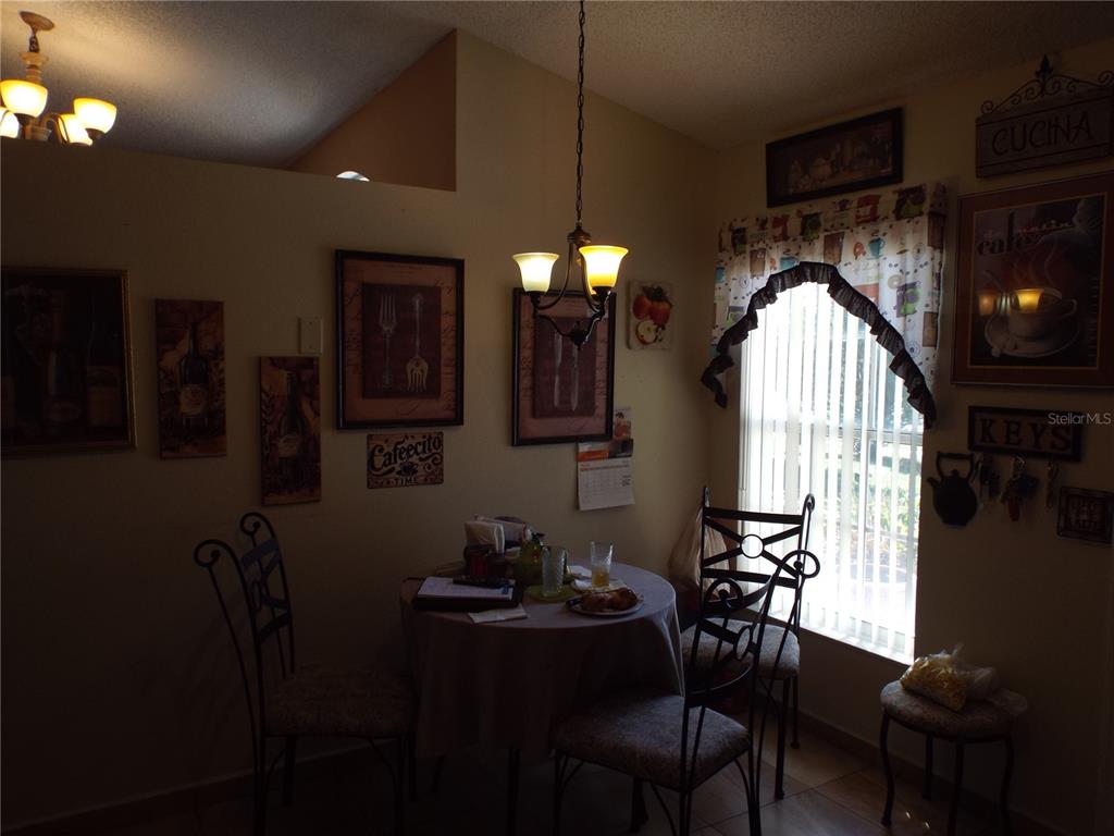 A dining area features a round table with chairs, a hanging light fixture, and wall art — 2546 SAGE DRIVE, KISSIMMEE, FL