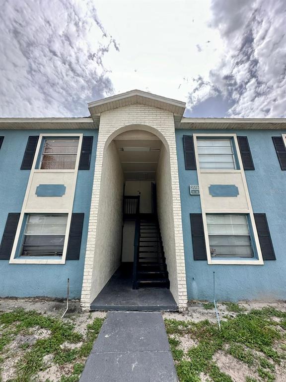 A low-angle exterior view of a blue two-story apartment building with a central stairwell — 2519 N ALAFAYA TRAIL UNIT 34, ORLANDO, FL