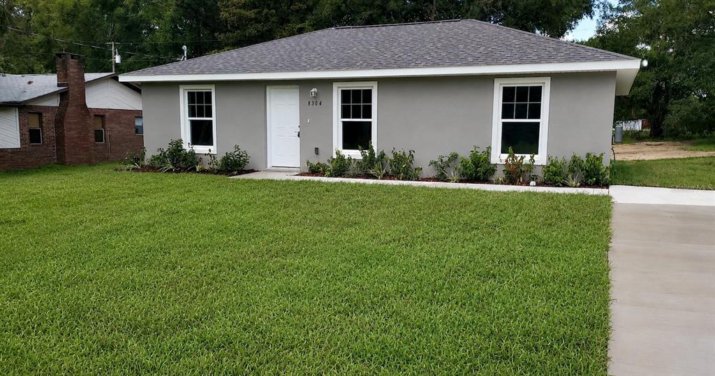 A single-story gray house with a white door and three windows sits on a lawn — 20864 SW STARLING DRIVE, DUNNELLON, FL