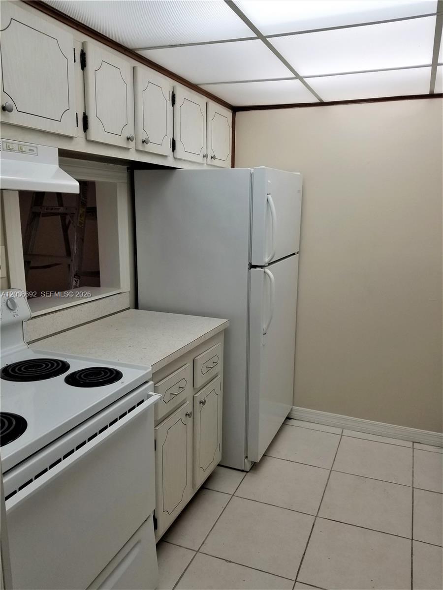 A kitchen features white appliances, light-colored cabinets, a tiled floor, and a drop ceiling — 14201 N Kendall Dr # 405D, Miami FL 33186, MIAMI, FL