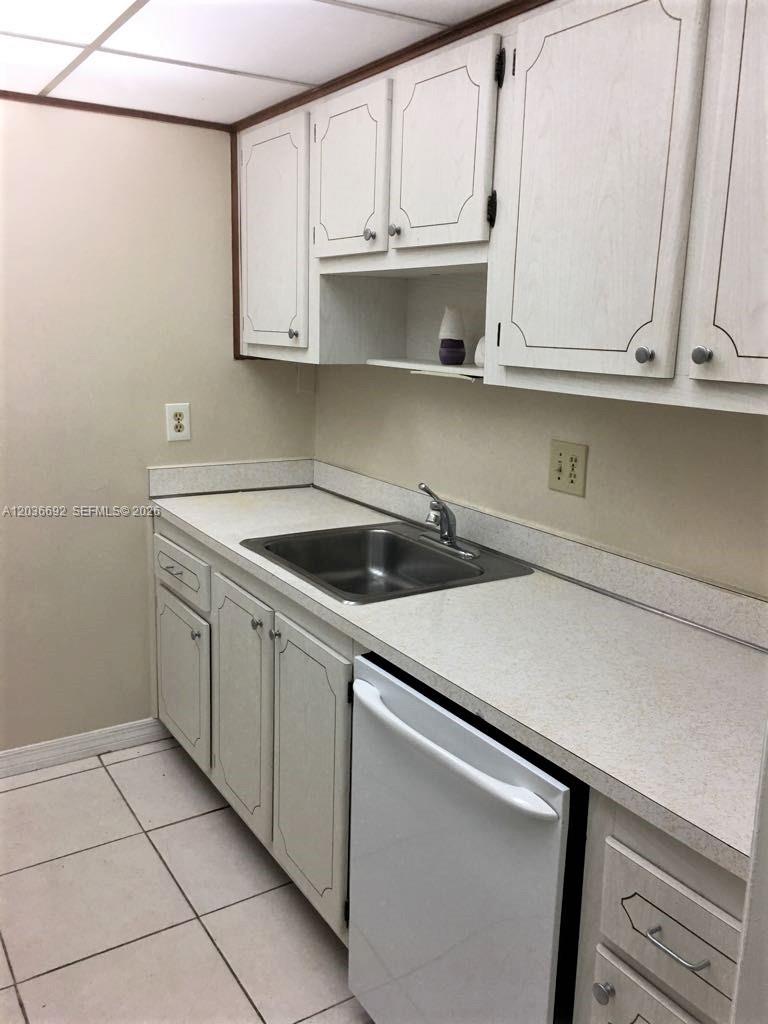 A kitchen features white cabinets, a stainless steel sink, and a white dishwasher — 14201 N Kendall Dr # 405D, Miami FL 33186, MIAMI, FL