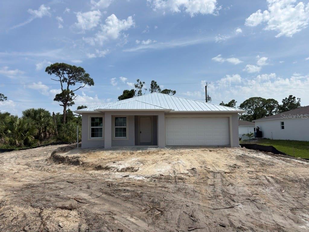 A newly constructed single-story house with a metal roof and a two-car garage — 26257 BROOKS ROAD, PUNTA GORDA, FL