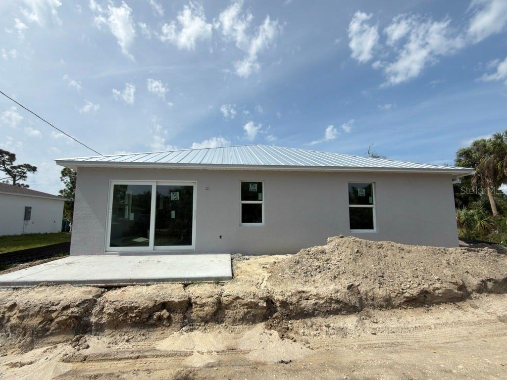 The exterior rear view of a new construction house features a concrete patio and dirt — 26257 BROOKS ROAD, PUNTA GORDA, FL
