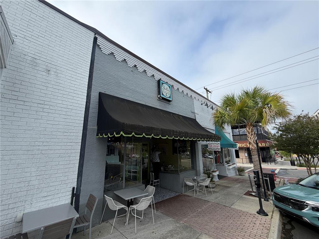 The exterior of a gray brick commercial building features a black awning and outdoor seating — 20 SW BROADWAY STREET UNIT A, OCALA, FL