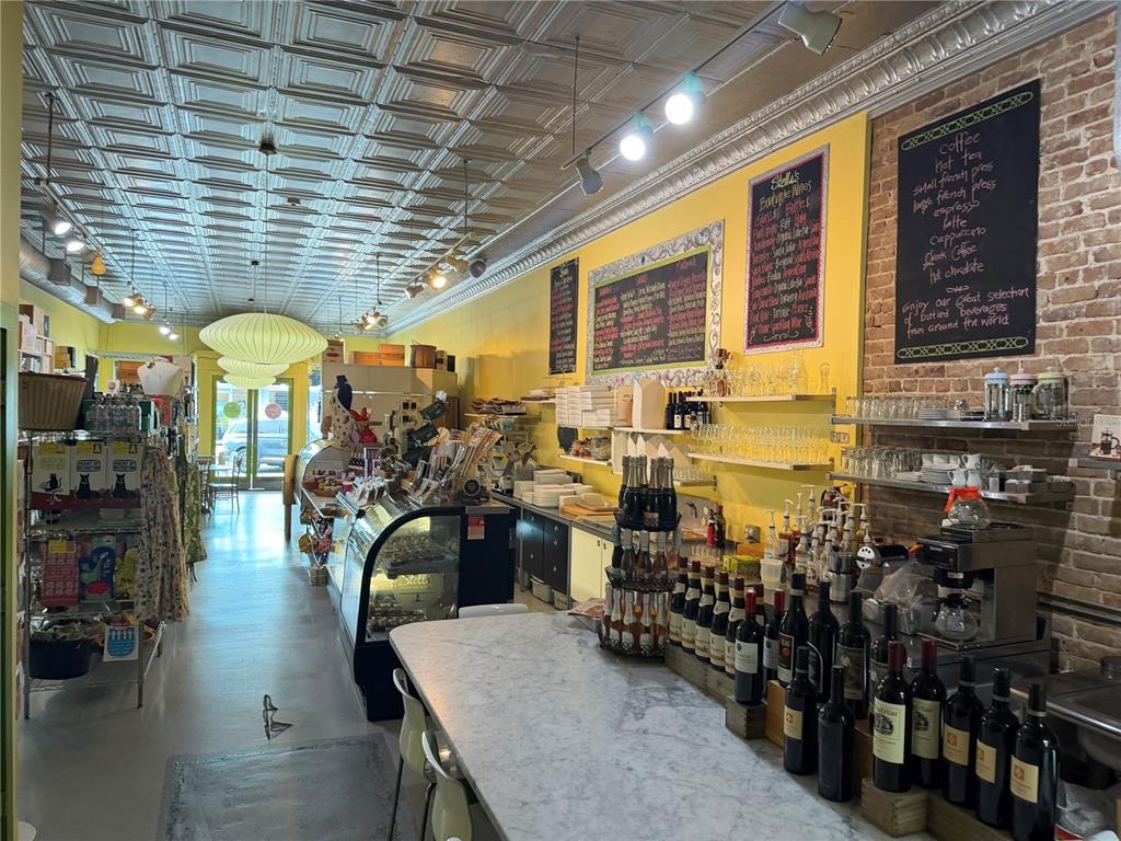 A cafe interior features a marble counter, yellow walls, exposed brick, and a decorative tin ceiling — 20 SW BROADWAY STREET UNIT A, OCALA, FL
