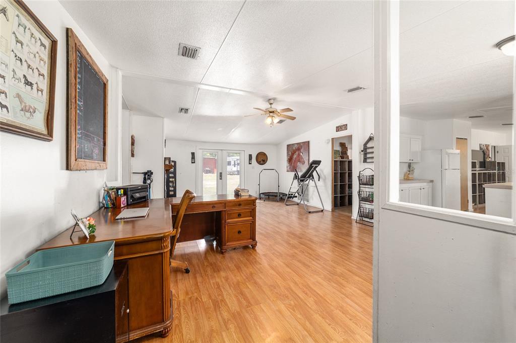 A home office with a wooden desk, laminate flooring, and a view into the kitchen — 19551 SE 42ND PLACE, MORRISTON, FL