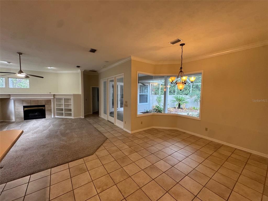 A dining area with tile flooring and a bay window adjacent to a carpeted living room — 4404 SW 91ST DRIVE, GAINESVILLE, FL