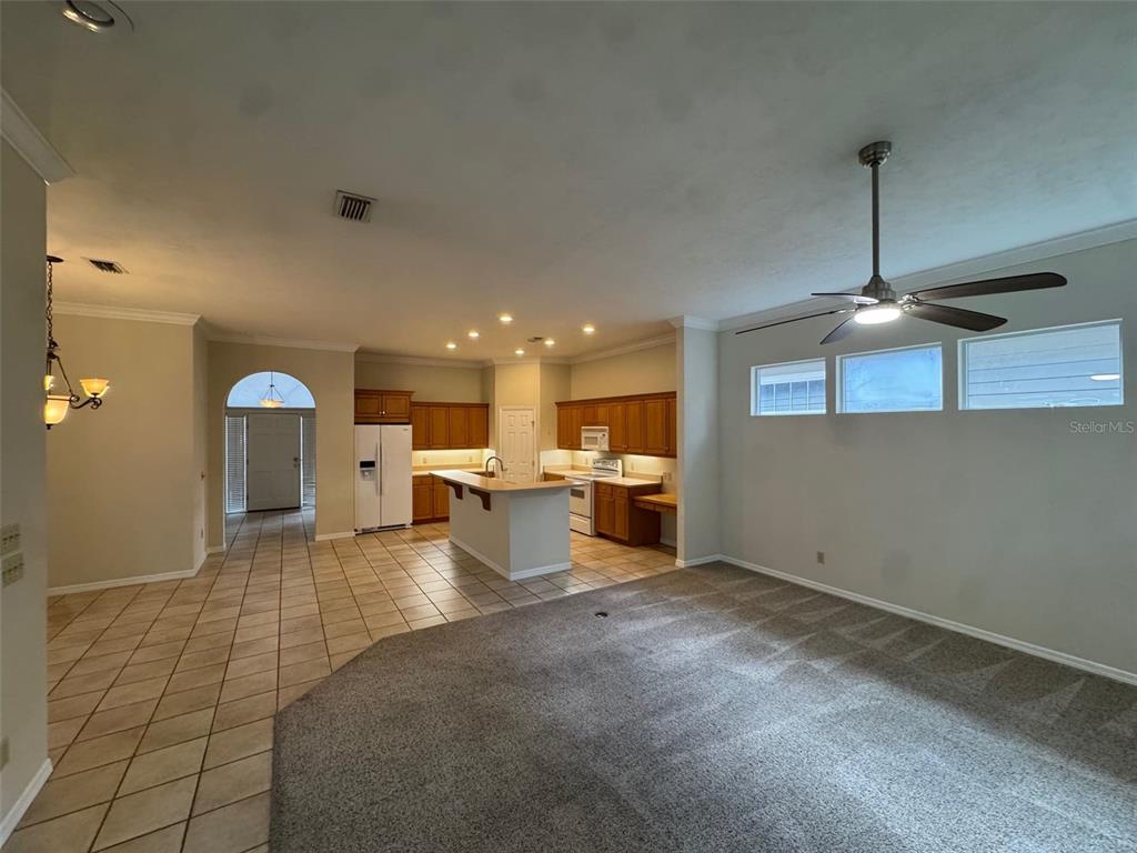 A kitchen with wood cabinets and a center island opens to a carpeted living area — 4404 SW 91ST DRIVE, GAINESVILLE, FL