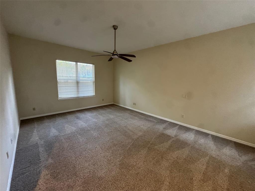 An empty bedroom with beige walls, brown carpet, and a ceiling fan — 4404 SW 91ST DRIVE, GAINESVILLE, FL