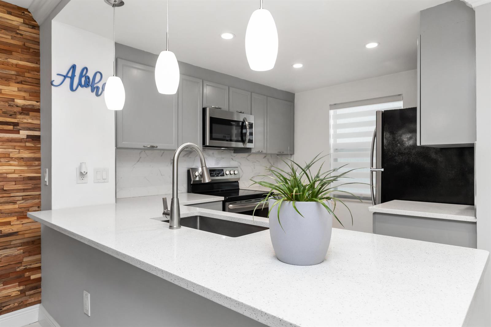 A kitchen with gray cabinets, white quartz countertops, a stainless steel sink, and pendant lighting — 9780 Marina Boulevard # 421, Boca Raton FL 33428, BOCA RATON, FL