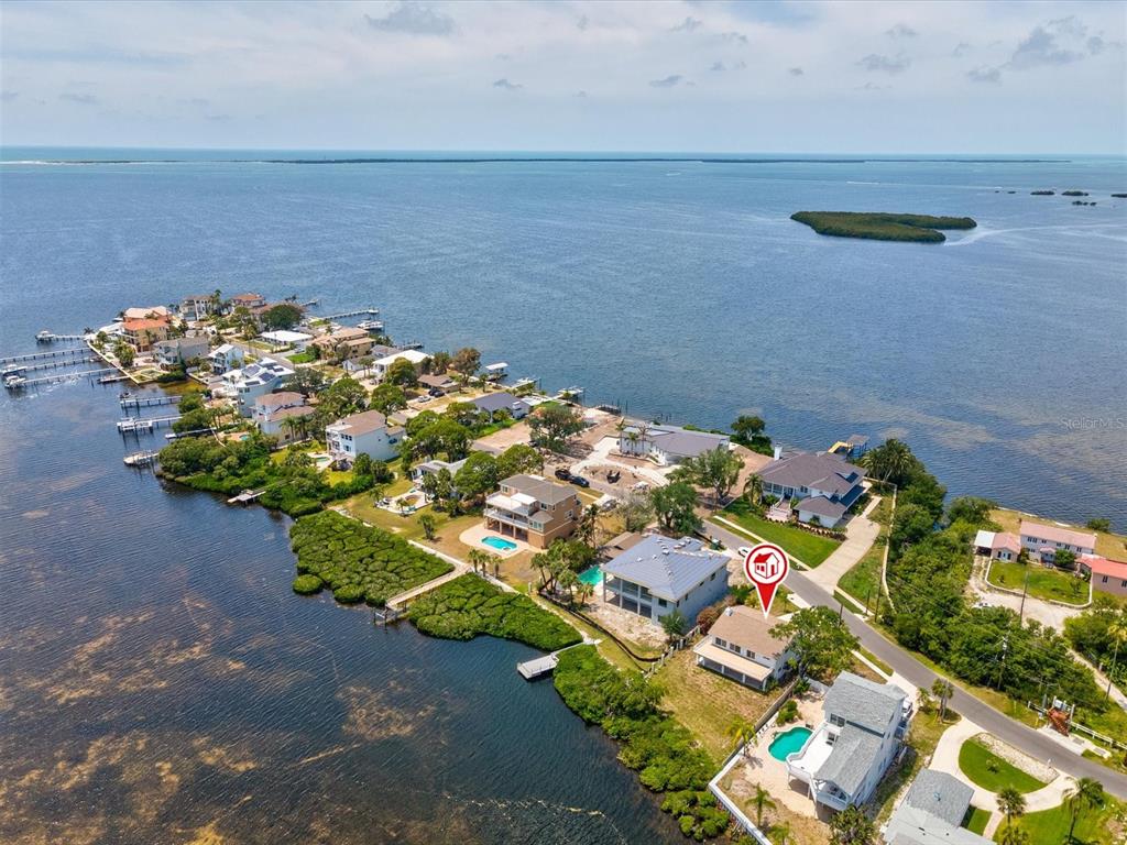 An aerial view shows a coastal neighborhood with several houses, swimming pools, and docks — 1647 SEA BREEZE DRIVE, TARPON SPRINGS, FL