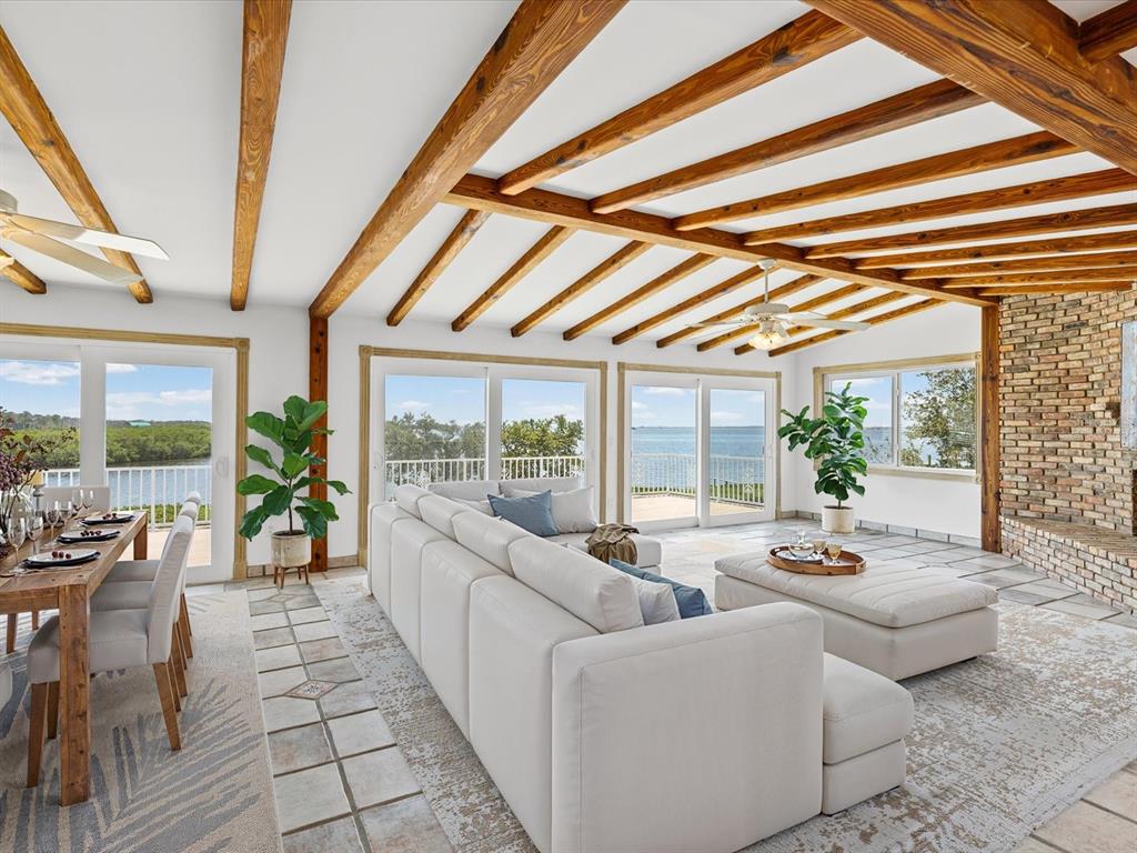 A living and dining room with exposed wood beams, tile floors, and waterfront views — 1647 SEA BREEZE DRIVE, TARPON SPRINGS, FL