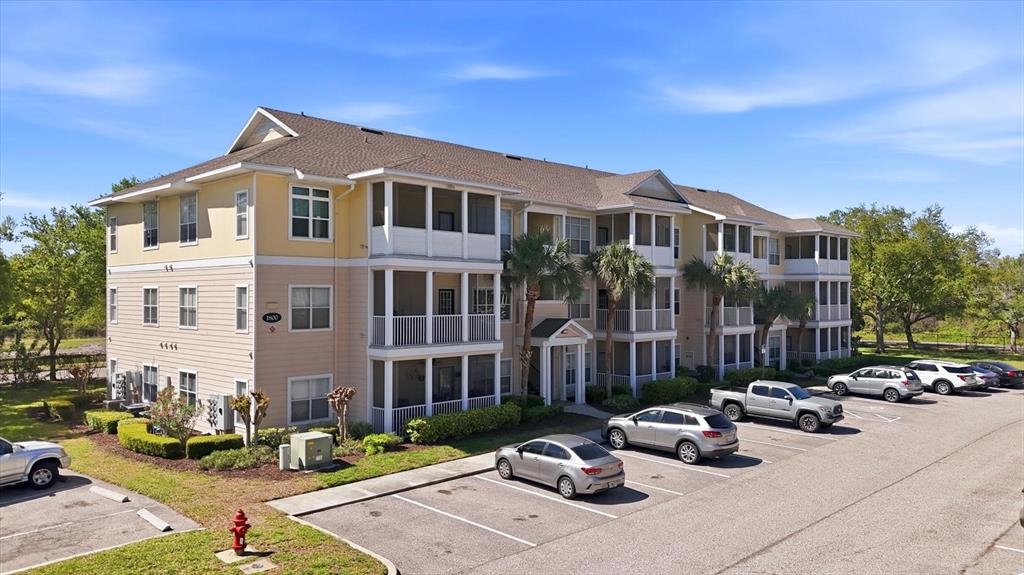 An exterior view of a three-story apartment building with a parking lot in front — 4802 51ST STREET W UNIT 1801, BRADENTON, FL