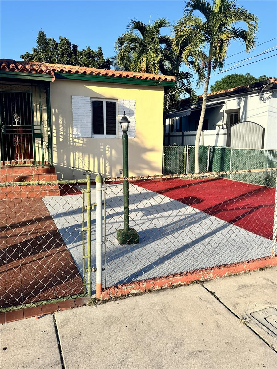 A yellow house with a red and grey driveway behind a chain-link fence — 3445 NW 2nd St, Miami FL 33125, MIAMI, FL