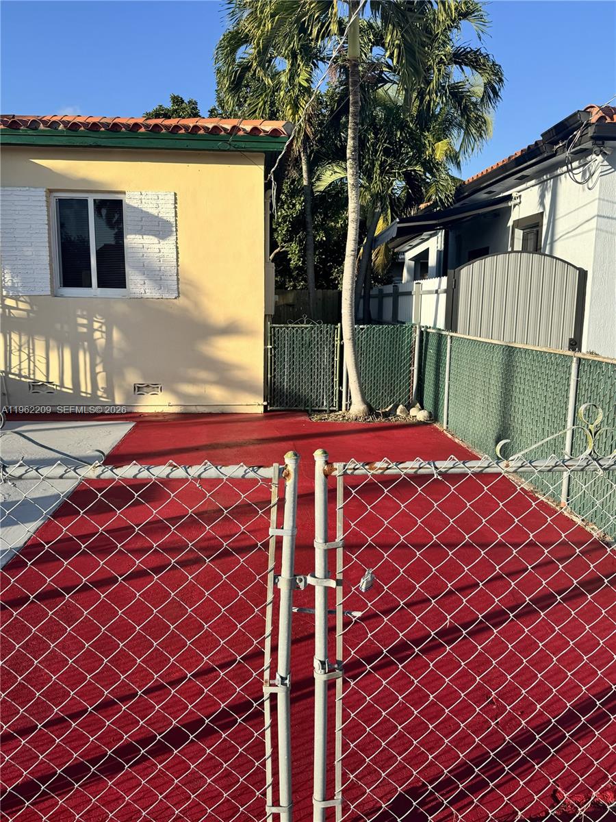 A fenced-in backyard features a red-painted concrete patio and a tall palm tree — 3445 NW 2nd St, Miami FL 33125, MIAMI, FL