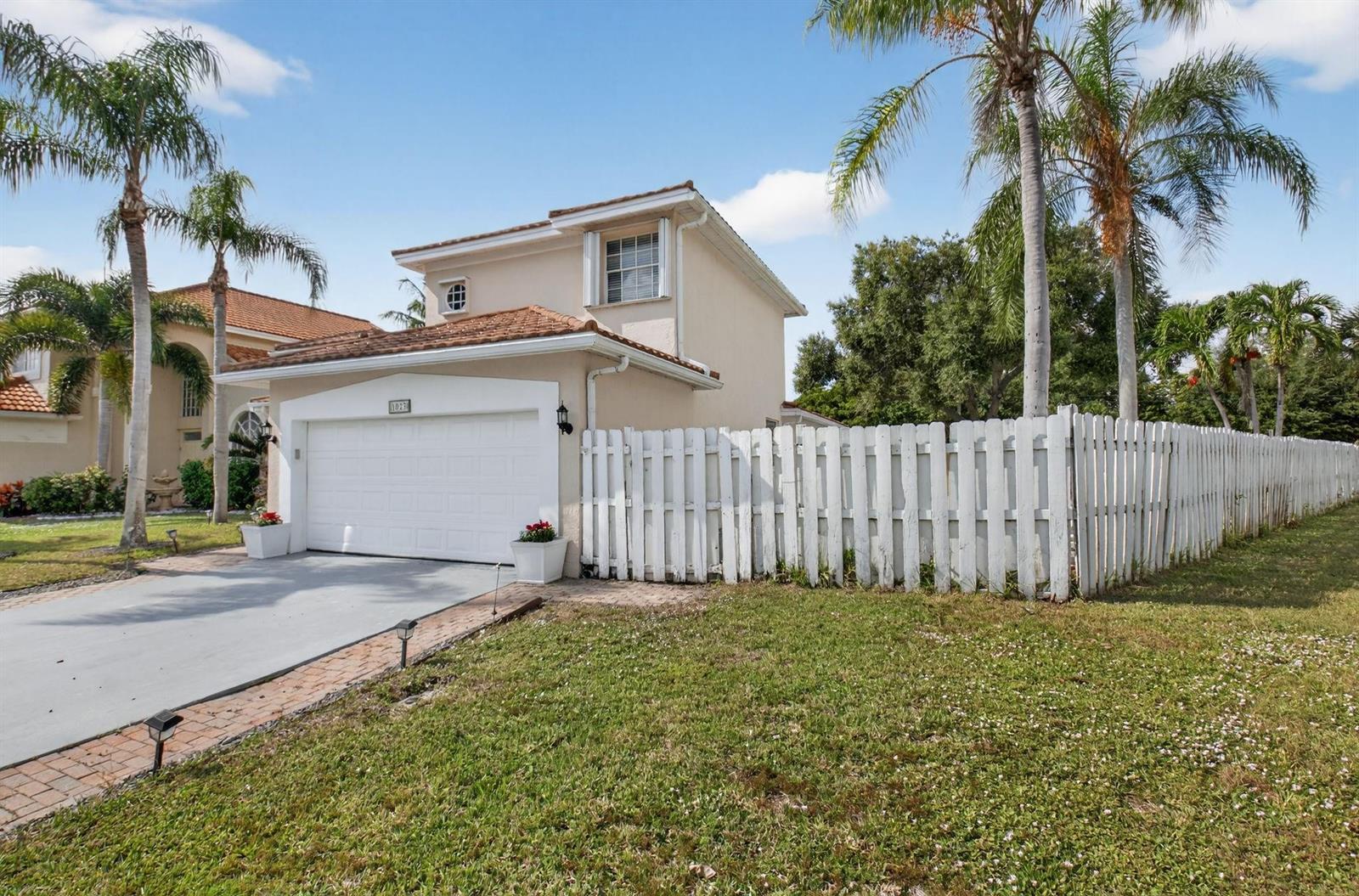 A two-story beige house with a white garage door and a white picket fence — 1023 Fairfax Circle, Boynton Beach FL 33436, BOYNTON BEACH, FL