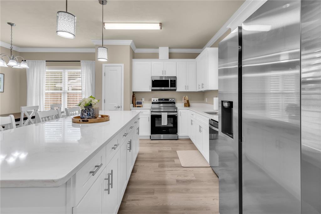 A modern kitchen features white cabinetry, stainless steel appliances, and a large central island — 23781 NW 193RD AVENUE, HIGH SPRINGS, FL