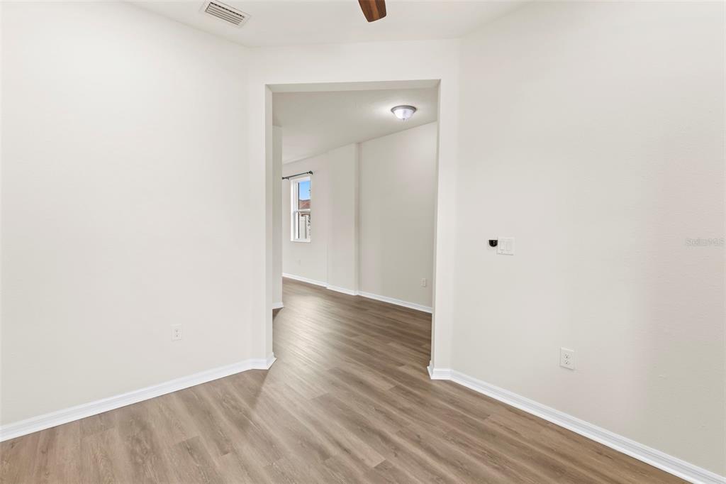 An interior view shows a room with light-colored walls and wood-look flooring leading into another space — 12210 MOSS LAKE LOOP, NEW PORT RICHEY, FL