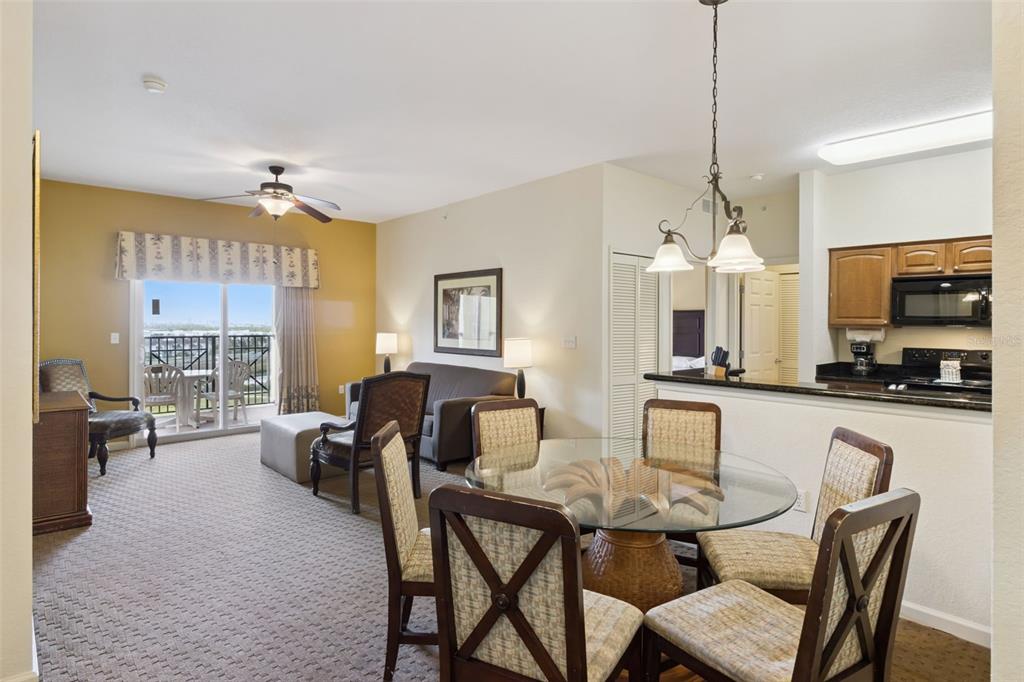 A dining area with a glass table sits before a living room with a balcony view — 8101 RESORT VILLAGE DRIVE UNIT 31110, ORLANDO, FL