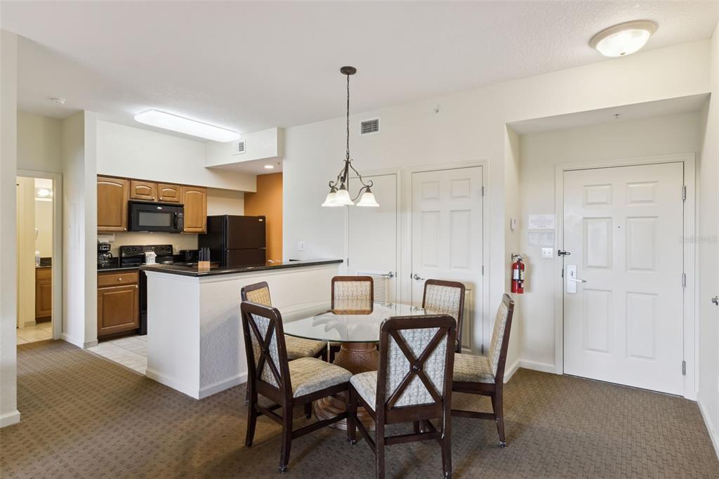 A dining area with a glass table and chairs sits adjacent to a small kitchen — 8101 RESORT VILLAGE DRIVE UNIT 31110, ORLANDO, FL