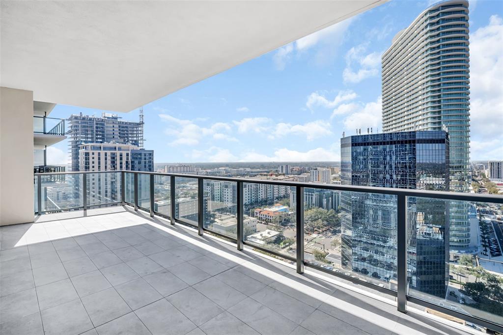 A high-rise balcony with gray tile flooring and a glass railing overlooking a city skyline — 275 1ST AVENUE S UNIT 2001, ST PETERSBURG, FL