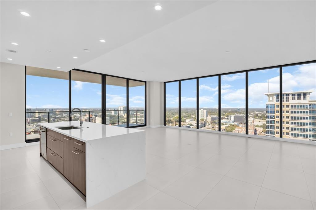 A modern kitchen island with white countertops sits in an open-plan room with floor-to-ceiling windows — 275 1ST AVENUE S UNIT 2001, ST PETERSBURG, FL