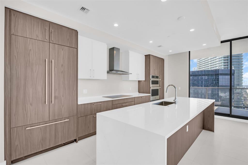 A modern kitchen features a large white island, wood-toned cabinetry, and floor-to-ceiling windows — 275 1ST AVENUE S UNIT 2001, ST PETERSBURG, FL