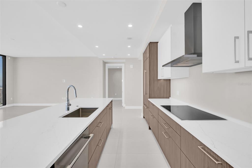 A modern kitchen features white countertops, wood-toned cabinets, a stainless steel sink, and a cooktop — 275 1ST AVENUE S UNIT 2001, ST PETERSBURG, FL