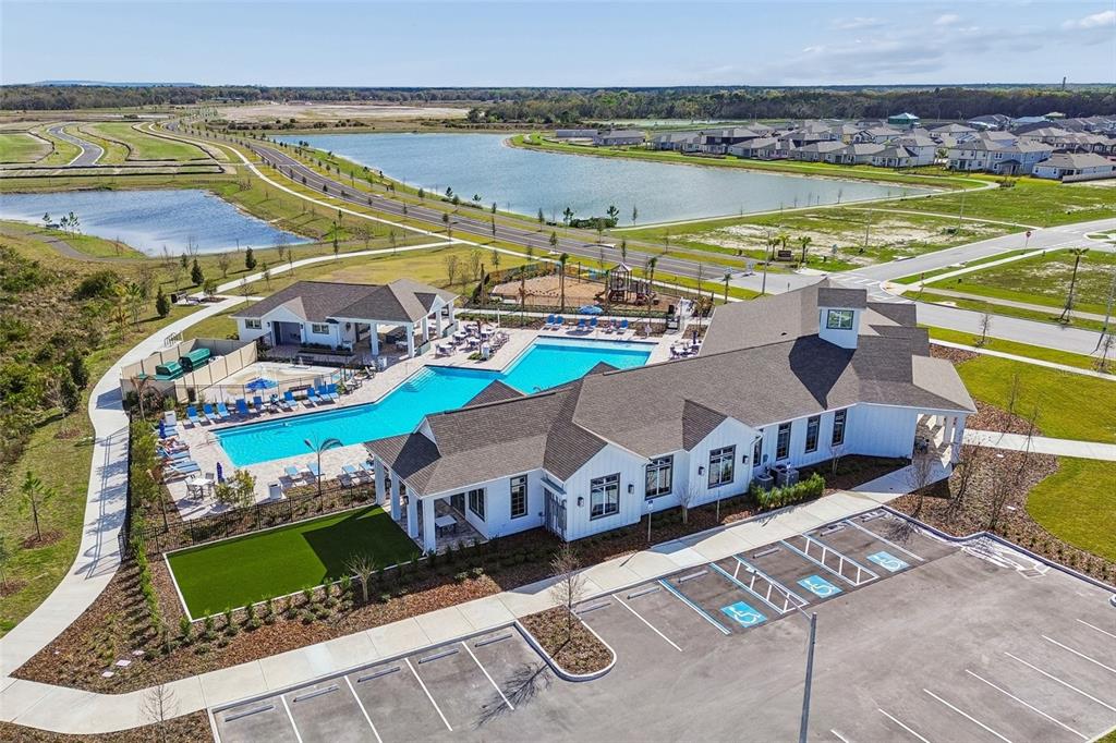 An aerial view shows a community clubhouse with a swimming pool, playground, and parking lot — 5571 FREESIA DRIVE, LAKELAND, FL