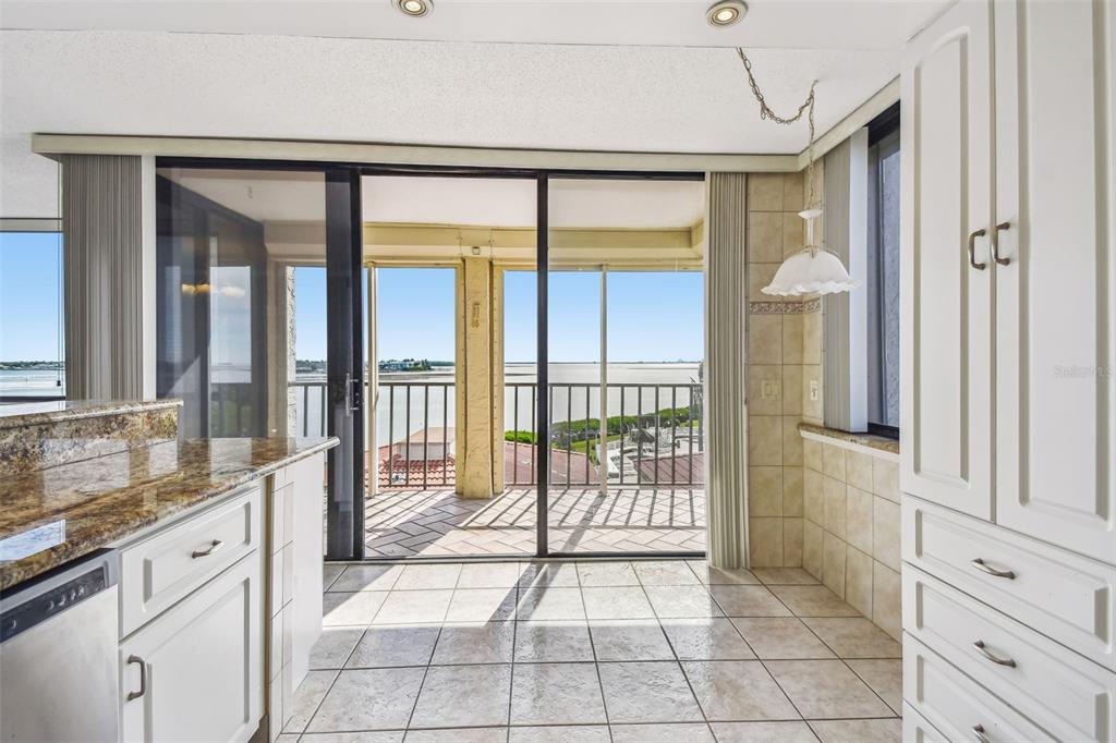 A kitchen with white cabinets and granite countertops opens to a balcony overlooking the water — 6104 PALMA DEL MAR BOULEVARD S UNIT 402, ST PETERSBURG, FL