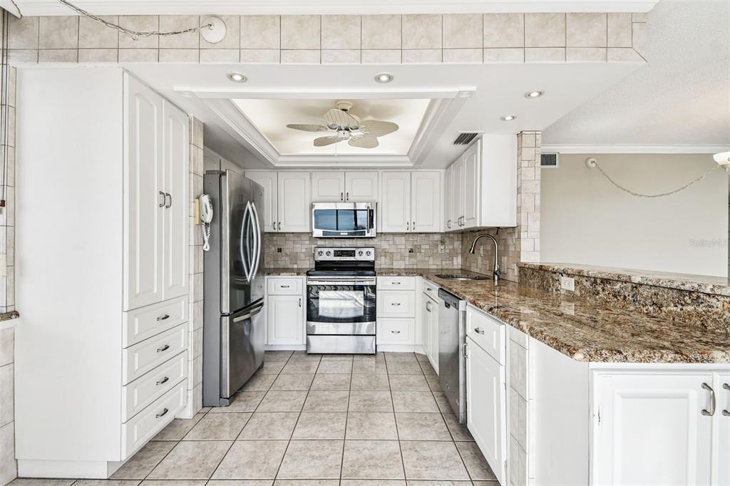 A kitchen with white cabinets, stainless steel appliances, granite countertops, and tiled floors — 6104 PALMA DEL MAR BOULEVARD S UNIT 402, ST PETERSBURG, FL