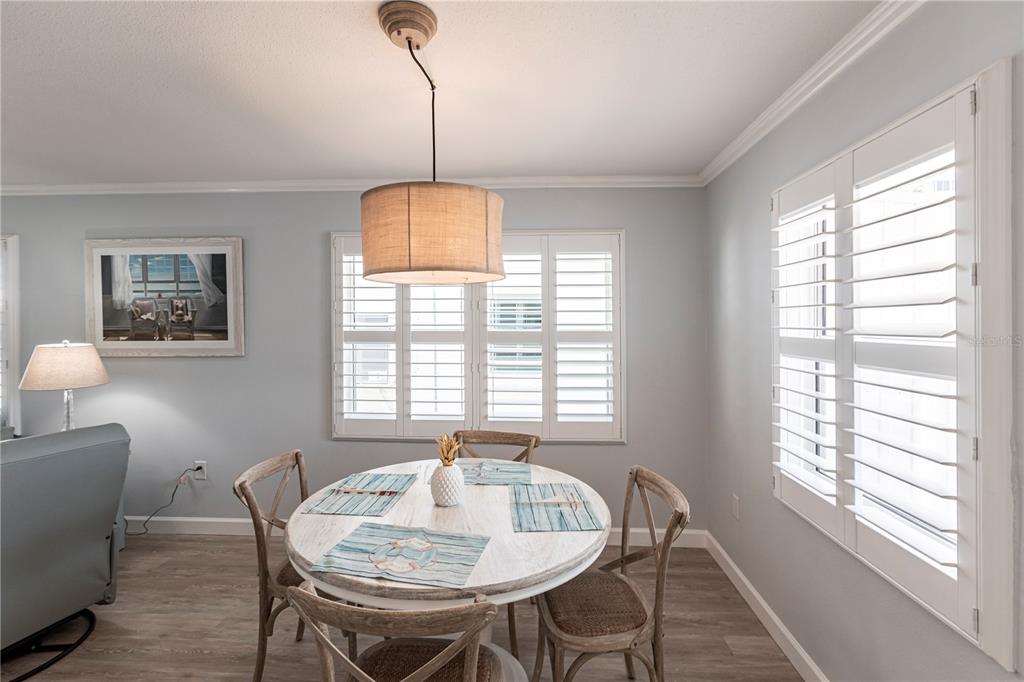 A dining area features a round white table, four wooden chairs, and plantation shutters — 6020 MIDNIGHT PASS ROAD UNIT 30, SARASOTA, FL