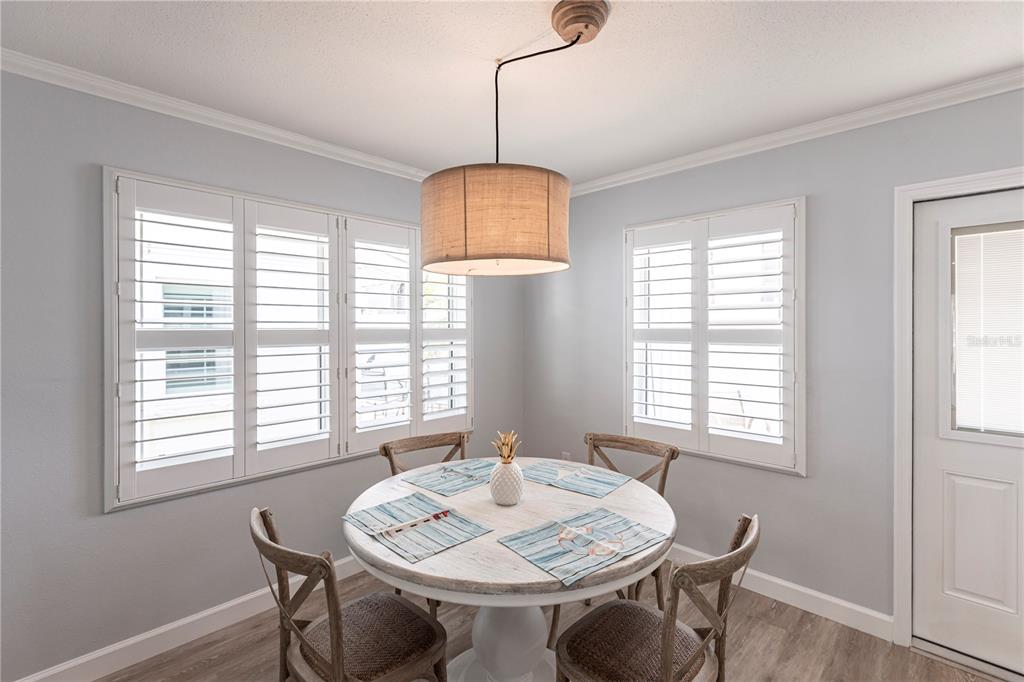 A dining area features a round white table, four wooden chairs, and plantation shutters — 6020 MIDNIGHT PASS ROAD UNIT 30, SARASOTA, FL