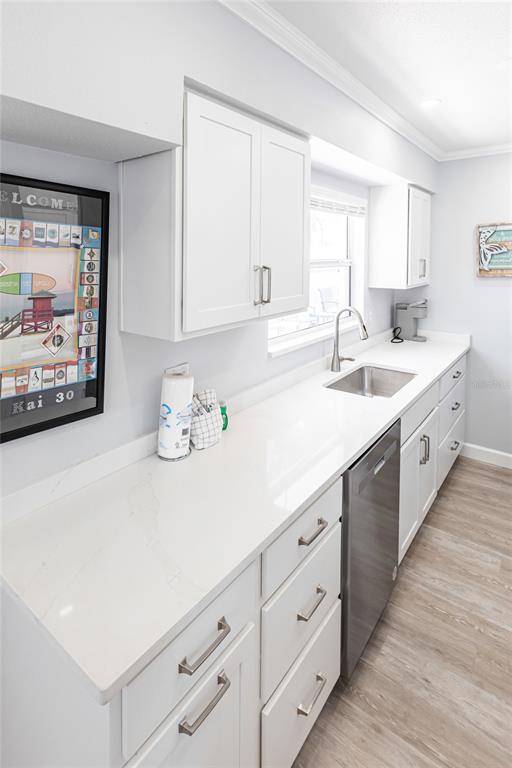 A bright kitchen features white cabinets, quartz countertops, a stainless steel dishwasher, and wood-look flooring — 6020 MIDNIGHT PASS ROAD UNIT 30, SARASOTA, FL