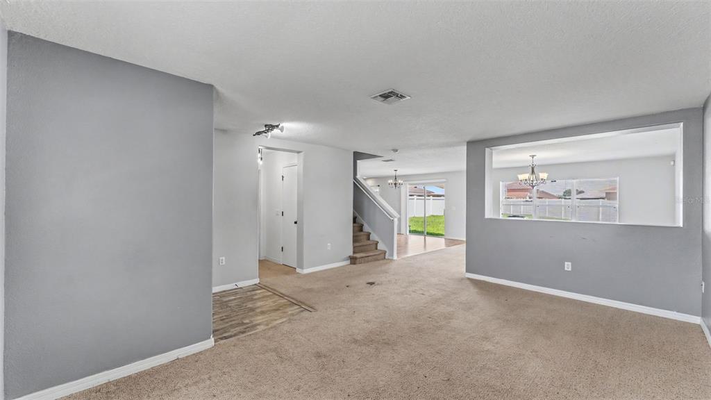 A carpeted living room features a pass-through window, a staircase, and a view of the backyard — 3014 YARROW LANE, MULBERRY, FL