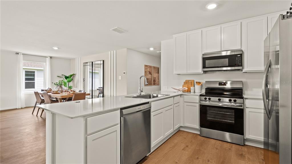 A modern kitchen with white cabinets, stainless steel appliances, and a quartz island countertop — 502 OAKCREEK LANE, DAVENPORT, FL