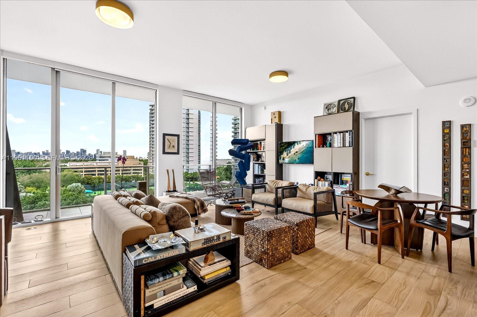 A modern living room with floor-to-ceiling windows, light wood floors, and contemporary furniture — 2678 Tigertail Ave # 604, Miami FL 33133, MIAMI, FL