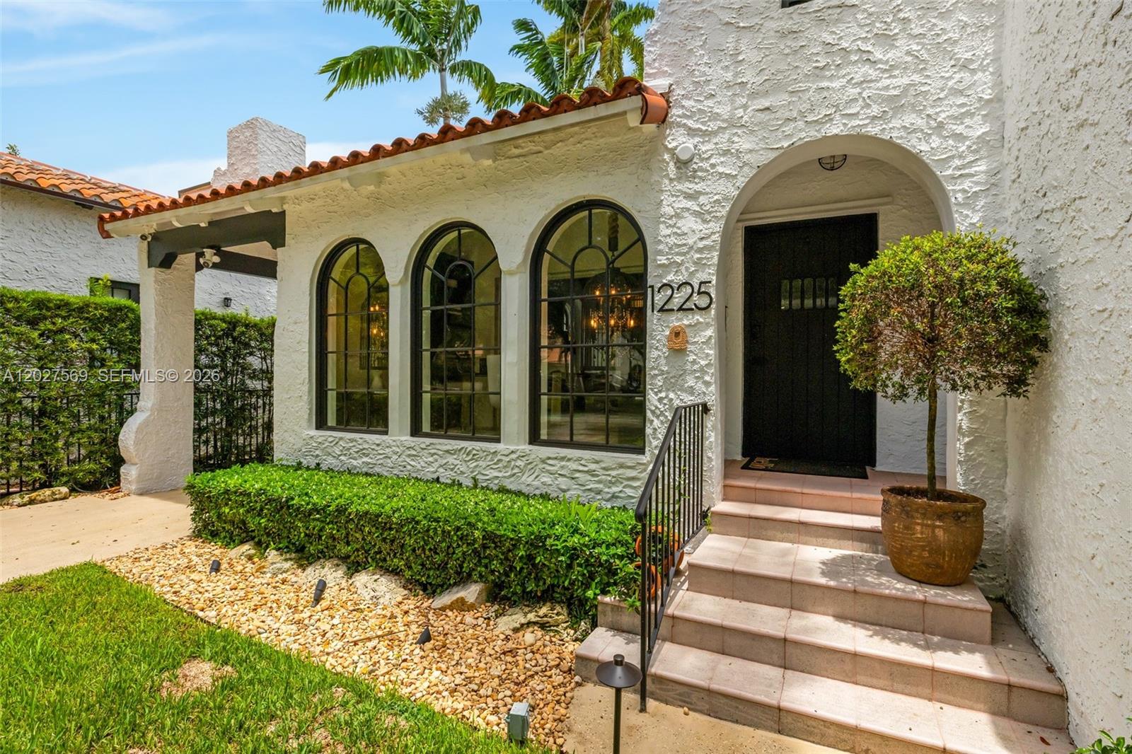 The exterior of a white stucco house features arched windows, a tiled roof, and steps — 1225 Alhambra Cir, Coral Gables FL 33134, CORAL GABLES, FL