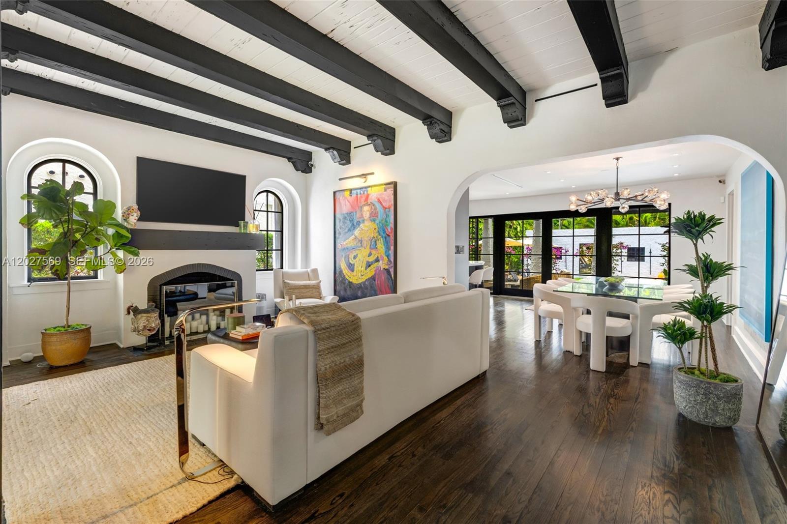 A living room and dining area with dark wood floors, white walls, and exposed ceiling beams — 1225 Alhambra Cir, Coral Gables FL 33134, CORAL GABLES, FL