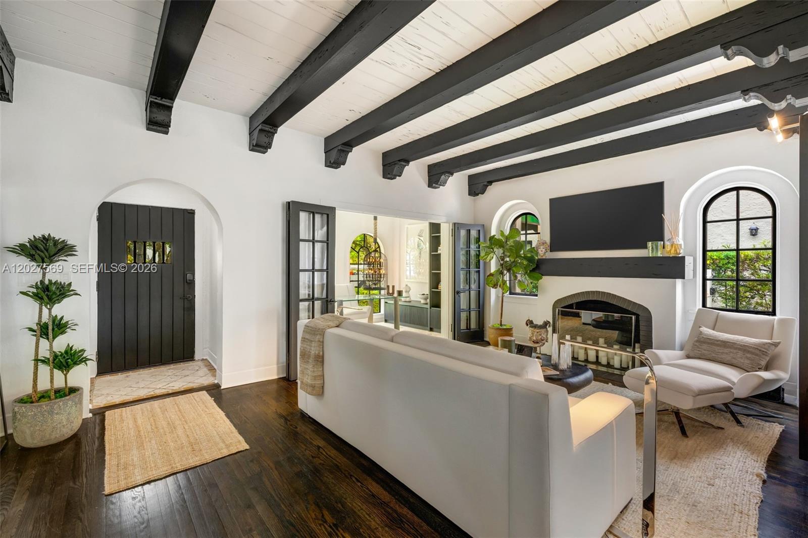 A living room features dark wood floors, exposed black ceiling beams, and a white fireplace — 1225 Alhambra Cir, Coral Gables FL 33134, CORAL GABLES, FL