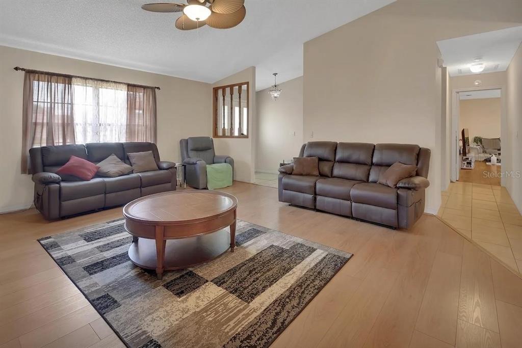 A living room features two brown leather sofas, a round coffee table, and wood flooring — 7330 SE 109TH PLACE, BELLEVIEW, FL