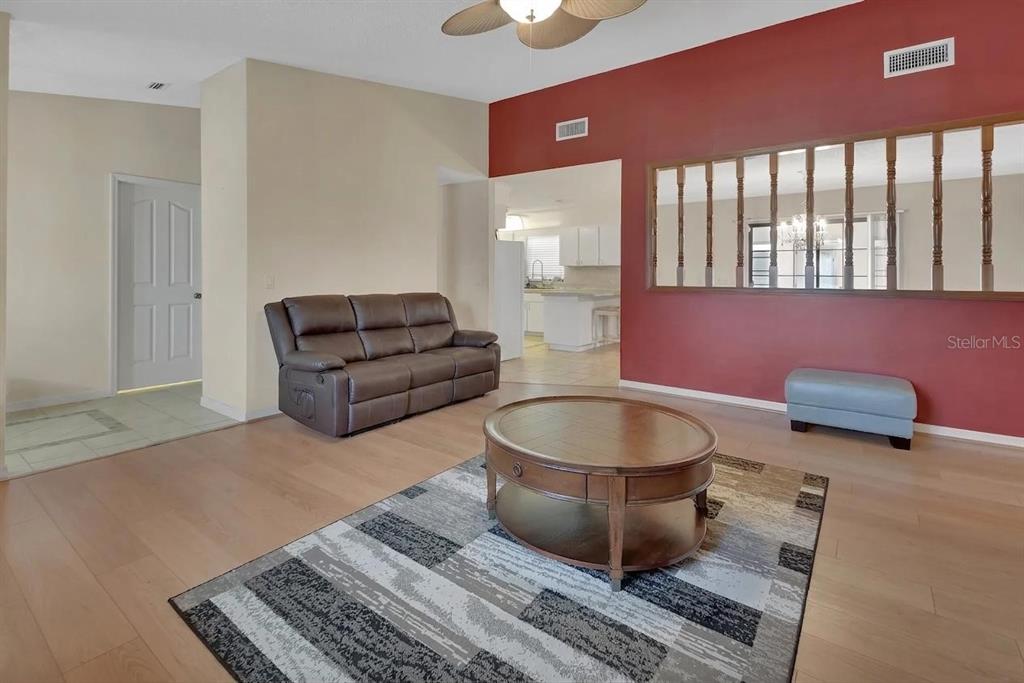 A living room features a brown sofa, a round coffee table, and a red accent wall — 7330 SE 109TH PLACE, BELLEVIEW, FL