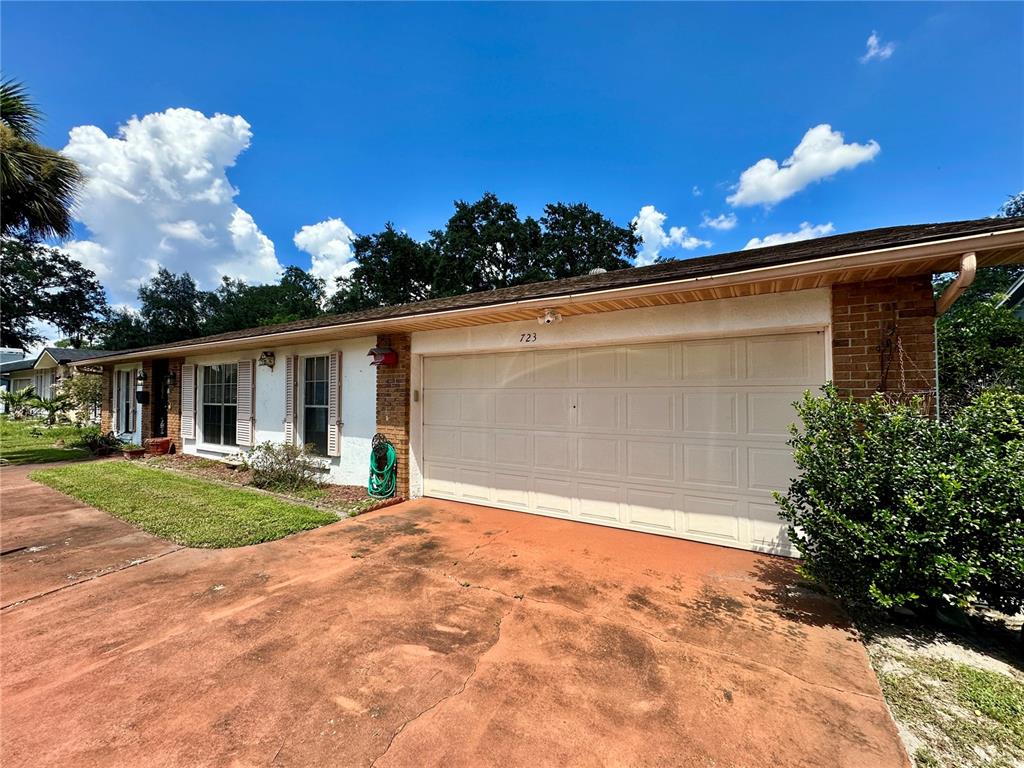 A single-story house with a brick facade, white garage door, and a red concrete driveway — 723 GASTON FOSTER ROAD, ORLANDO, FL