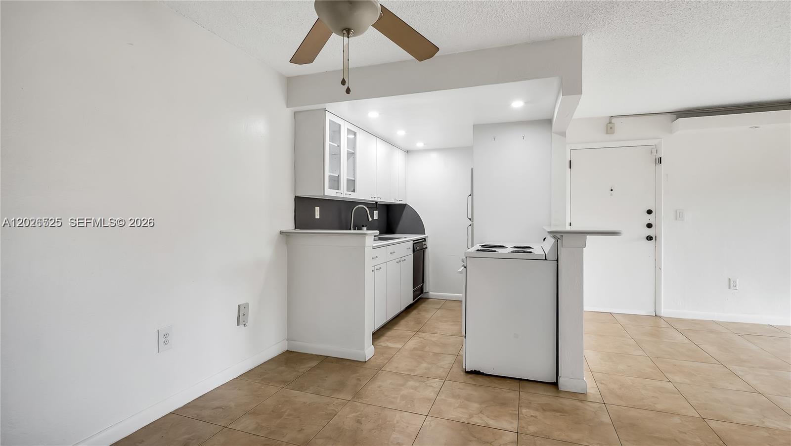 A small kitchen features white cabinets, a white stove, and light brown tile flooring — 7200 Fairway Dr # H12, Miami Lakes FL 33014, MIAMI LAKES, FL