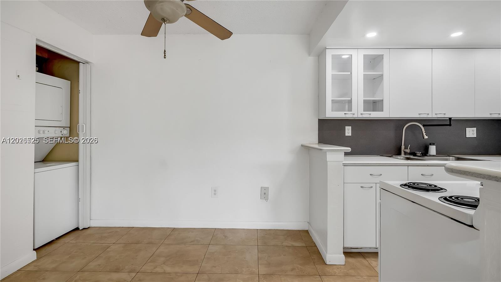A kitchen features white cabinets, a tiled floor, and an adjacent laundry closet — 7200 Fairway Dr # H12, Miami Lakes FL 33014, MIAMI LAKES, FL